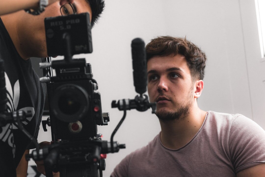A tense looking professional sitting stiffly in front of a camera during a practice interview